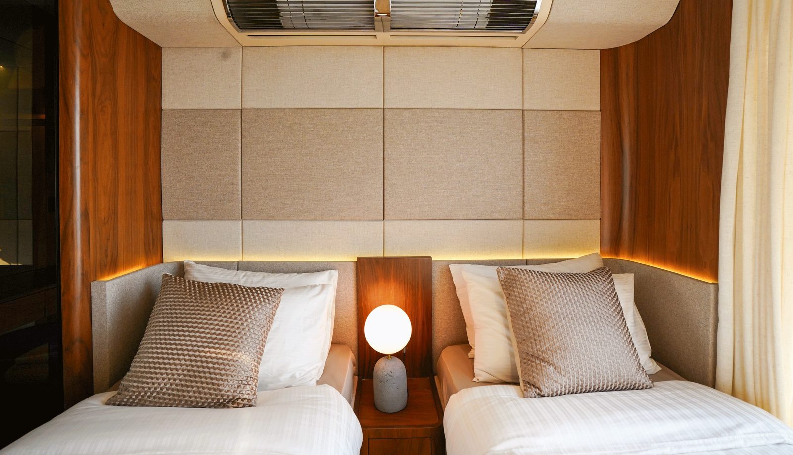 Guest cabin with two single beds and upholstered headboard wall