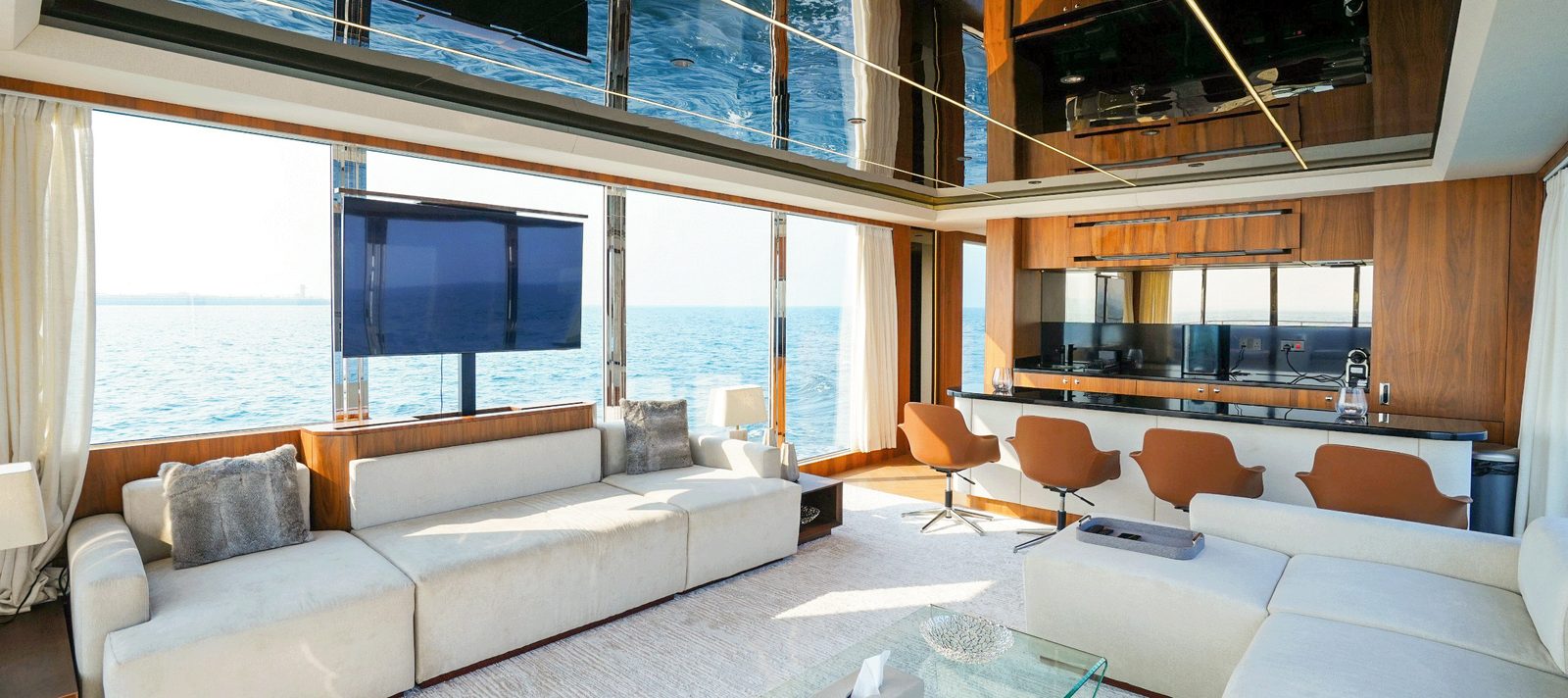 Main saloon with wrap-around sofas, dining area and panoramic windows