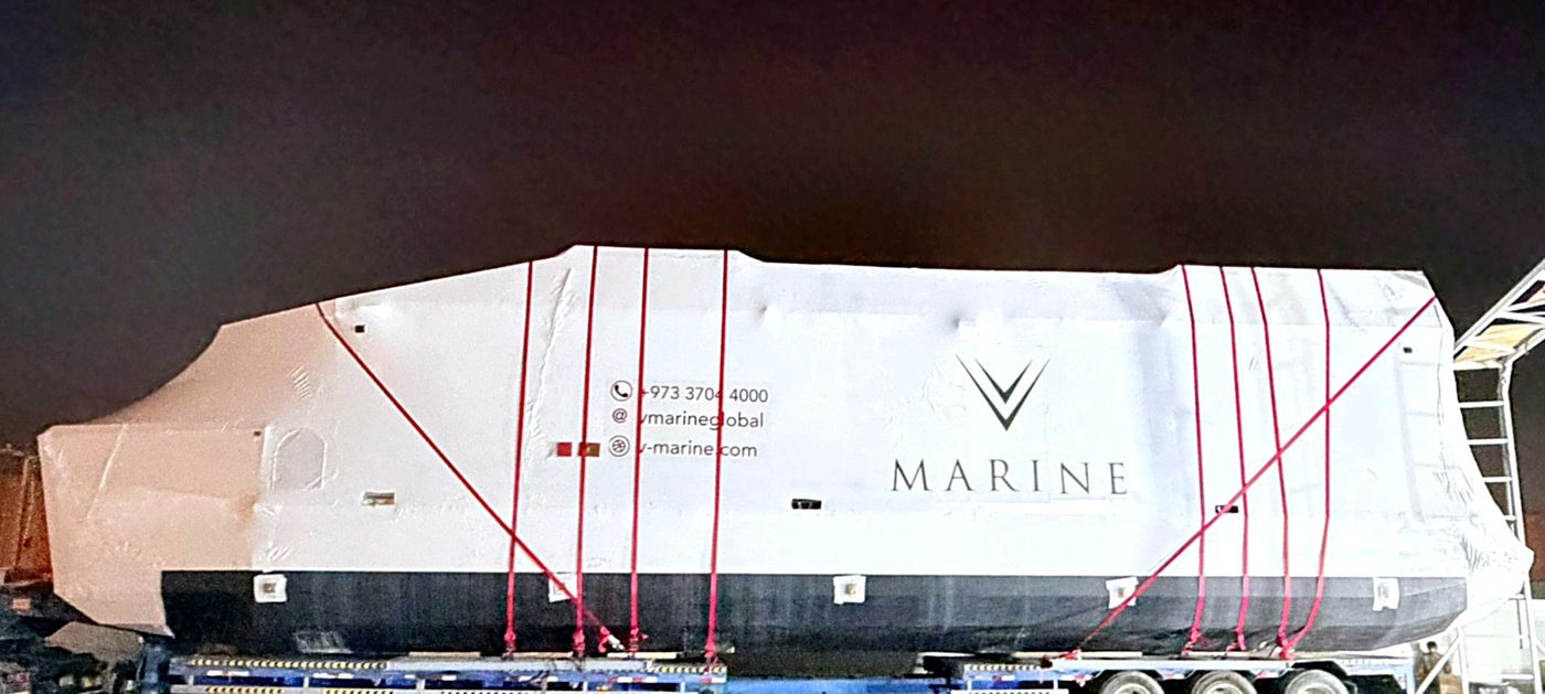 A shrink-wrapped, V-Marine branded hull strapped down on a trailer for shipping